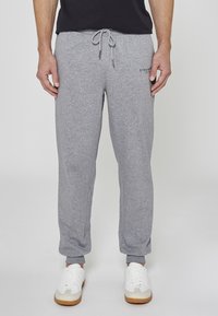 Hallid dressipüksid, mis on valmistatud pehmest kangast ja millel on elastsed mansetid. Vöökohal on pael ja reiel pisike logo. Kandmiseks valgete tossudega.