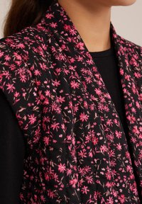 Fekete virágmintás sál, rózsaszín virágmintával, steppelt textúrával és puha anyagfelülettel. A dizájn széles gallérstílust tartalmaz.