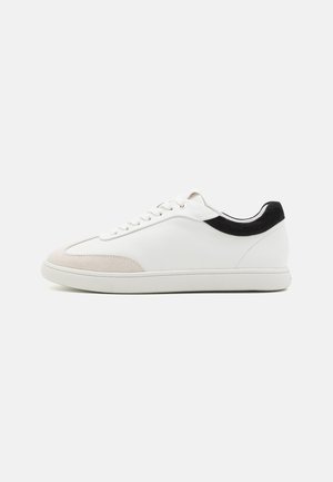Baskets en cuir blanc avec des accents en daim beige, talon noir, bout rond et semelle plate en caoutchouc. Présentent des lacets blancs et un design minimaliste.