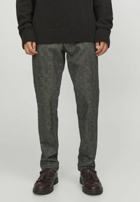 Pantaloni grigi strutturati in tessuto intrecciato. Presentano una vestibilità slim con un motivo sottile, abbinati a scarpe marroni.