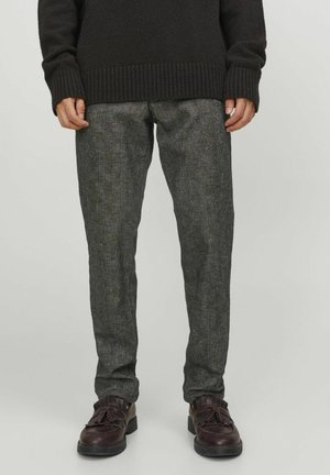 Pantaloni grigi strutturati in tessuto intrecciato. Presentano una vestibilità slim con un motivo sottile, abbinati a scarpe marroni.