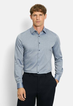 Hellblaues Langarmhemd mit dezentem Muster, Knopfverschluss vorne und dunklen Knöpfen. Kombiniert mit marineblauen Hosen im Slim Fit.