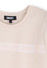 Beige DKNY t-shirt met een ronde halslijn, voorzien van een textuur logo band over de borst. Gladde stof met een aansluitende pasvorm.