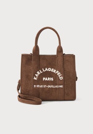 Brun ruskindstaske med to håndtag, en aftagelig skulderrem og hvid tekst med teksten "Karl Lagerfeld Paris 21 Rue St-Guillaume."