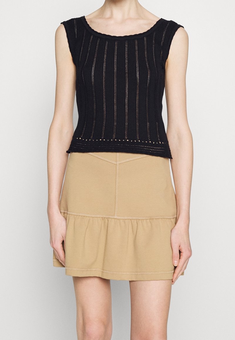 Top court en tricot noir avec des rayures verticales et un décolleté festonné, associé à une jupe échelonnée kaki avec des coutures contrastantes.