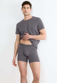 T-shirt grigio a maniche corte e slip coordinati. Tessuto morbido, design aderente e vita elastica con dettagli del logo.