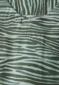 Groen gestreepte stof met een zebra-patroon, met variërende strookbreedtes en een gladde textuur met een V-hals ontwerp. De stiksels zijn zichtbaar langs de randen.
