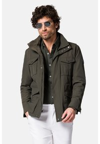 Jasnozielona, lekka kurtka z wieloma kieszeniami, zapinana na zamek i napy, o fakturowanej tkaninie. Mała naszywka z logo na lewym rękawie.