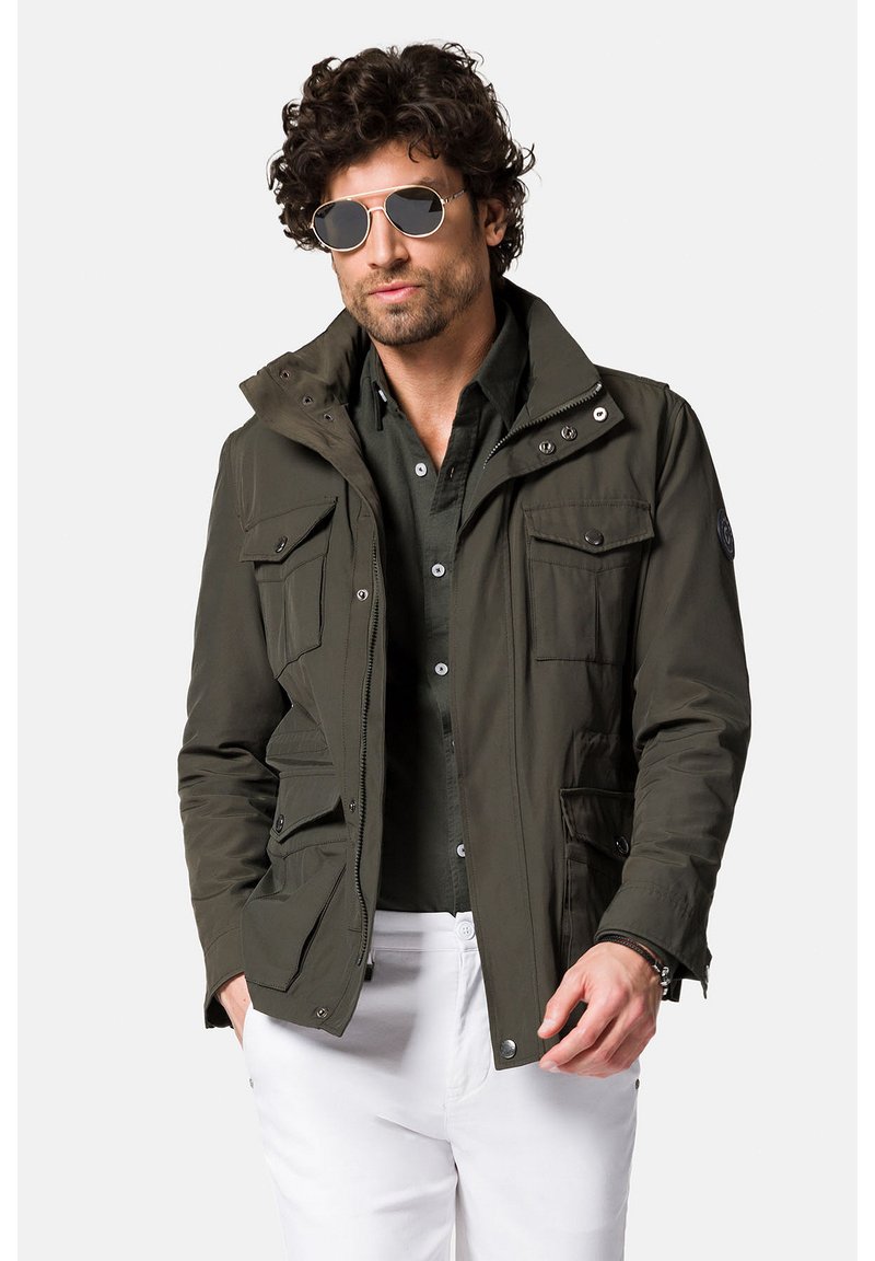 Jasnozielona, lekka kurtka z wieloma kieszeniami, zapinana na zamek i napy, o fakturowanej tkaninie. Mała naszywka z logo na lewym rękawie.