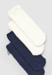 Calze pelose in tre colori: bianco, grigio chiaro e blu navy. Texture morbida con design della punta arrotondata. Ogni paio impilato verticalmente.