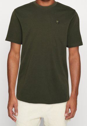 Olivgrön kortärmad t-shirt i bomull, med rund halsringning och en liten emblem på bröstet. Slät textur och avslappnad passform.