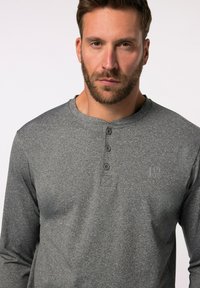 Graues Langarm-Henley-Shirt mit drei Knöpfen, einem runden Halsausschnitt und einem dezenten Logo auf der Brust. Weiche Stoffstruktur.