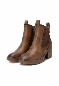 Botas de tobillo de cuero marrón con punta redondeada, paneles laterales elásticos y tacón en bloque texturizado. Presentan una cremallera lateral y lengüetas de agarre.