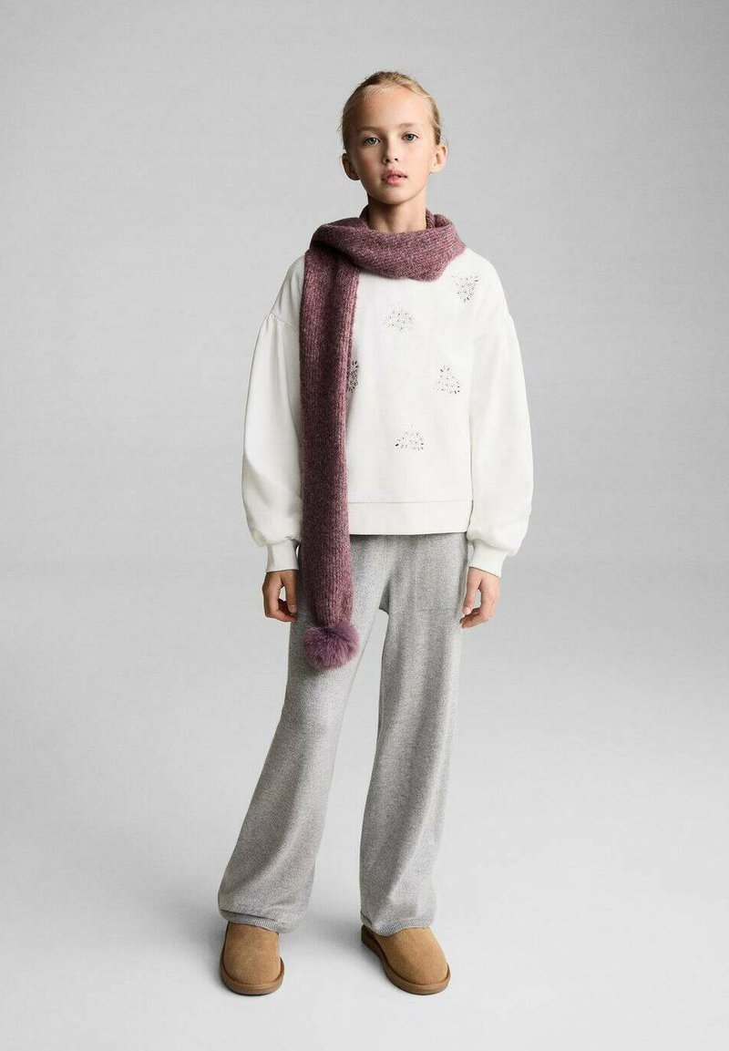 Felpa bianca con dettagli testurizzati, pantaloni grigi dalla vestibilità ampia e una lunga sciarpa bordeaux con pompon, abbinati a stivali slip-on beige.