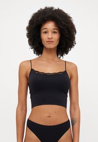 Top corto nero realizzato in tessuto liscio, con spalline sottili e un delicato pizzo lungo il scollo. Abbinato a una mutandina alta coordinata.