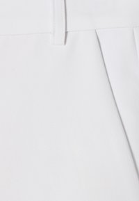 Tessuto bianco con una superficie liscia, dotato di un cinturino in vita e dettagli di pieghe sottili. Il materiale appare leggero e flessibile.