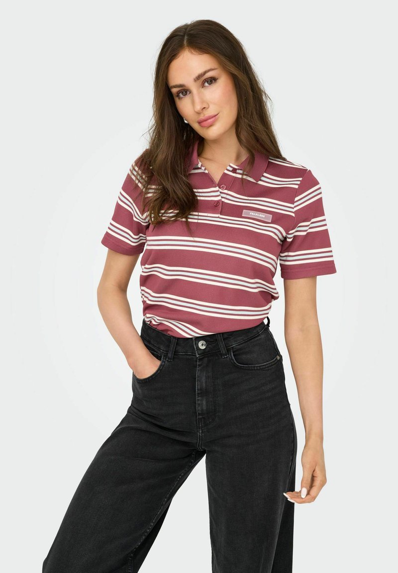 Vinröd och vitrandig polo med krage, tre knappar och en logopatch, i kombination med högmidjade svarta jeans.