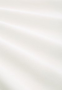 Weißer Stoff mit einer glatten, leicht strukturierten Oberfläche. Das Material zeigt sanfte Falten, die von weichem Licht beleuchtet werden.