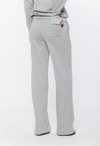 Jasnoszare dresy wykonane z miękkiego materiału, o prostym kroju, szerokich nogawkach oraz kieszeni z tyłu. Gładka faktura z minimalną ilością szwów.