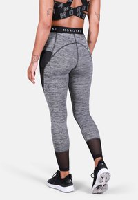 Szare legginsy sportowe o wysokim stanie z teksturowanym wykończeniem. Posiadają czarne siateczkowe panele po bokach i pasek z logo. Zestawione z czarnymi sneakersami.