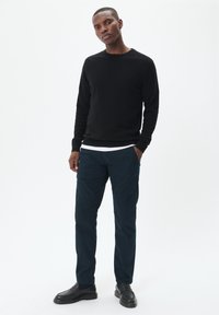Must musta, tumedad teklase ja mustad loaferid. Lihtne disain, tekstuurne kangas ja klassikaline lõige. Valge alussärk on nähtav.