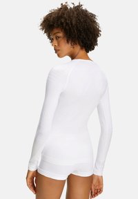Long-sleeve white athletic top with a fitted design and smooth texture. Features horizontal accents on sleeves and a round neckline.