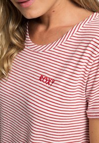 T-shirt à manches courtes rayé blanc et rouge, avec un logo "ROXY" brodé sur le côté gauche de la poitrine. Matière en coton doux.