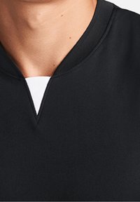 Svart t-shirt med rund hals och V-formad detalj i kragen, tillverkad av ett mjukt tyg, med en kontrasterande vit invändig halsringning.