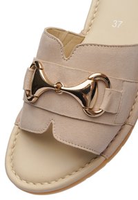 Béžová semišová sandála s otevřenou špičkou, zdobená tvarovaným výřezem a ozdobnou sponou v zlaté barvě na pásku. Velikost 37.