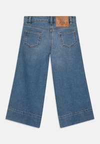 Džínové kalhoty culottes ve světle modré barvě s koženou nášivkou s logem, širokým střihem a dvěma zadními kapsami s kontrastním prošíváním.