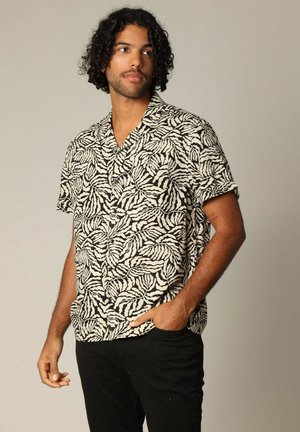 Chemise à manches courtes avec un motif de feuilles noir et blanc, en tissu léger, design col et coupe décontractée.
