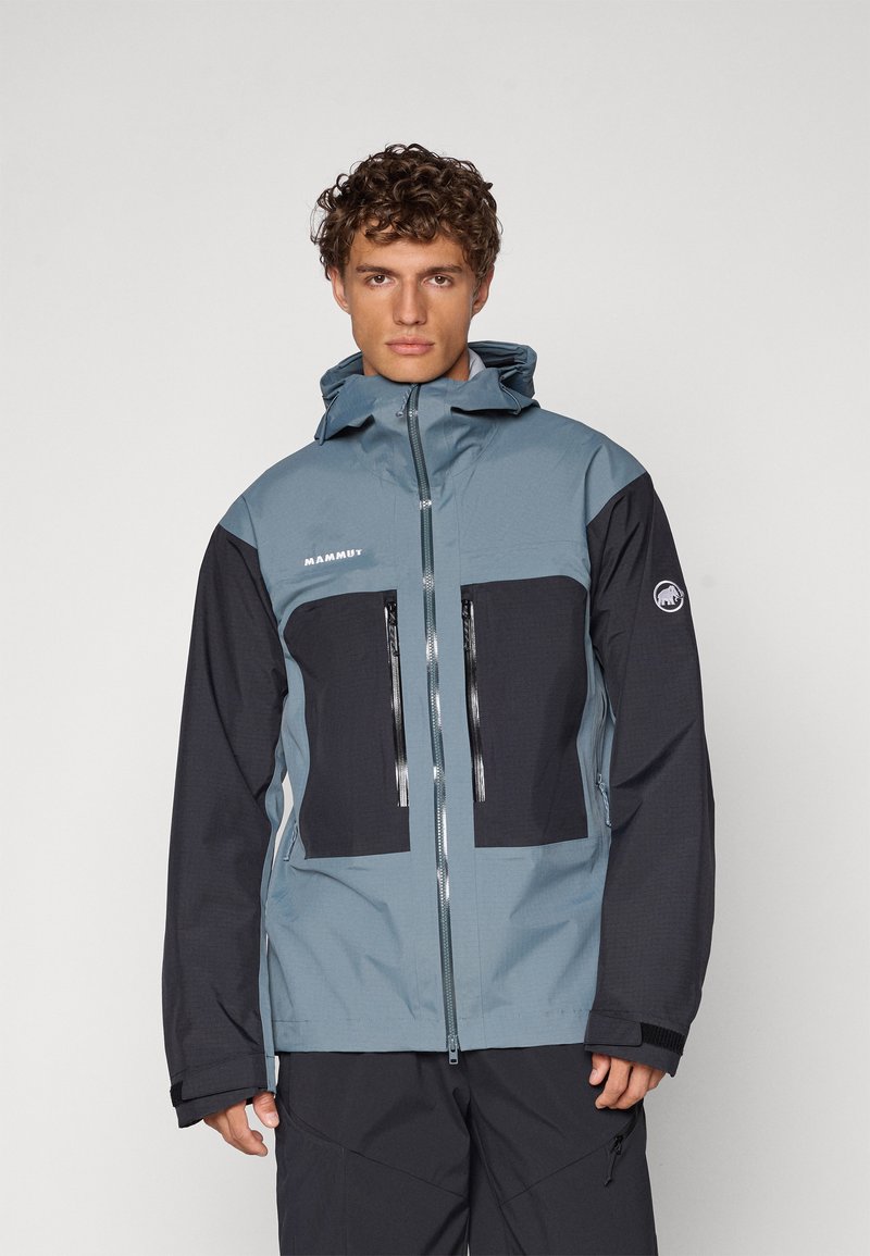 Men's Mammut jacket featuring a blue-gray upper with black sleeves and two zippered chest pockets; made from durable, weather-resistant material.