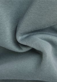 Tessuto morbido e stretch di colore grigio-blu chiaro, con una texture liscia e un sottile motivo di intreccio, adatto per applicazioni nel abbigliamento.