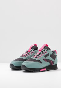 Sportovní boty s designem v tónech teal a černé, vyrobené z nubuku a síťoviny, s růžovými akcenty a podrážkou se zigzagovým vzorem.