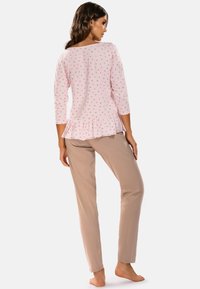 Top roz cu buline albe, având un tiv peplum, asortat cu pantaloni bej. Material moale, mâneci lungi și guler tip barcă.