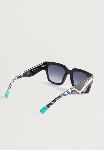Czarne okulary przeciwsłoneczne w kształcie kwadratu z gradientowymi szarymi soczewkami. Skrzydełka zdobione są wirującym czarno-białym wzorem z turkusowymi końcówkami i złotymi akcentami.