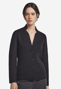 Svart stickad cardigan med V-ringning, femknappsstängning, två framfickor och långa ärmar. Tyget har ett texturerat mönster.
