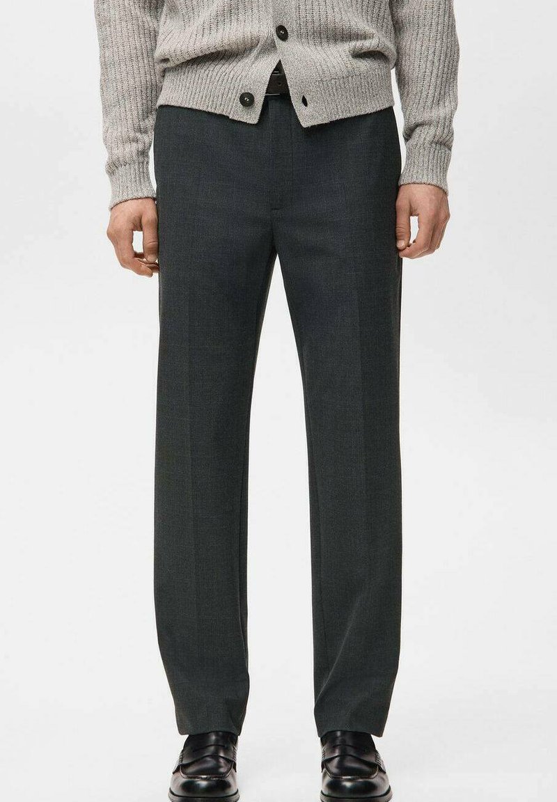 Dunkelgraue, maßgeschneiderte Hose mit geradem Schnitt, glatter Textur und dezenten Nadelstreifen, kombiniert mit einer hellgrauen, gerippten Strickjacke.