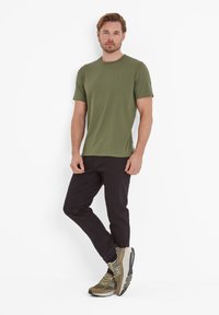 Olive green cotton t-shirt with short sleeves, paired with black trousers and olive-green sports shoes featuring grey accents and textured sole.