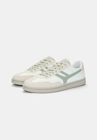 Sneakers z białą skórzaną cholewką, jasnoszarymi zamszowymi akcentami, perforowanym noskiem i zielonym wzorem w paski. Sznurowane z płaską podeszwą.