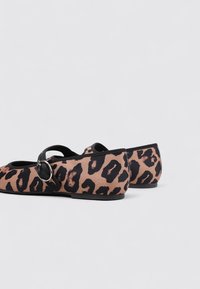 Leopardenmuster Ballerinas mit runder Zehe, schwarzen Akzenten und einem Riemen mit einer silbernen Schnalle. Aus einem Stoff mit glatter Textur gefertigt.