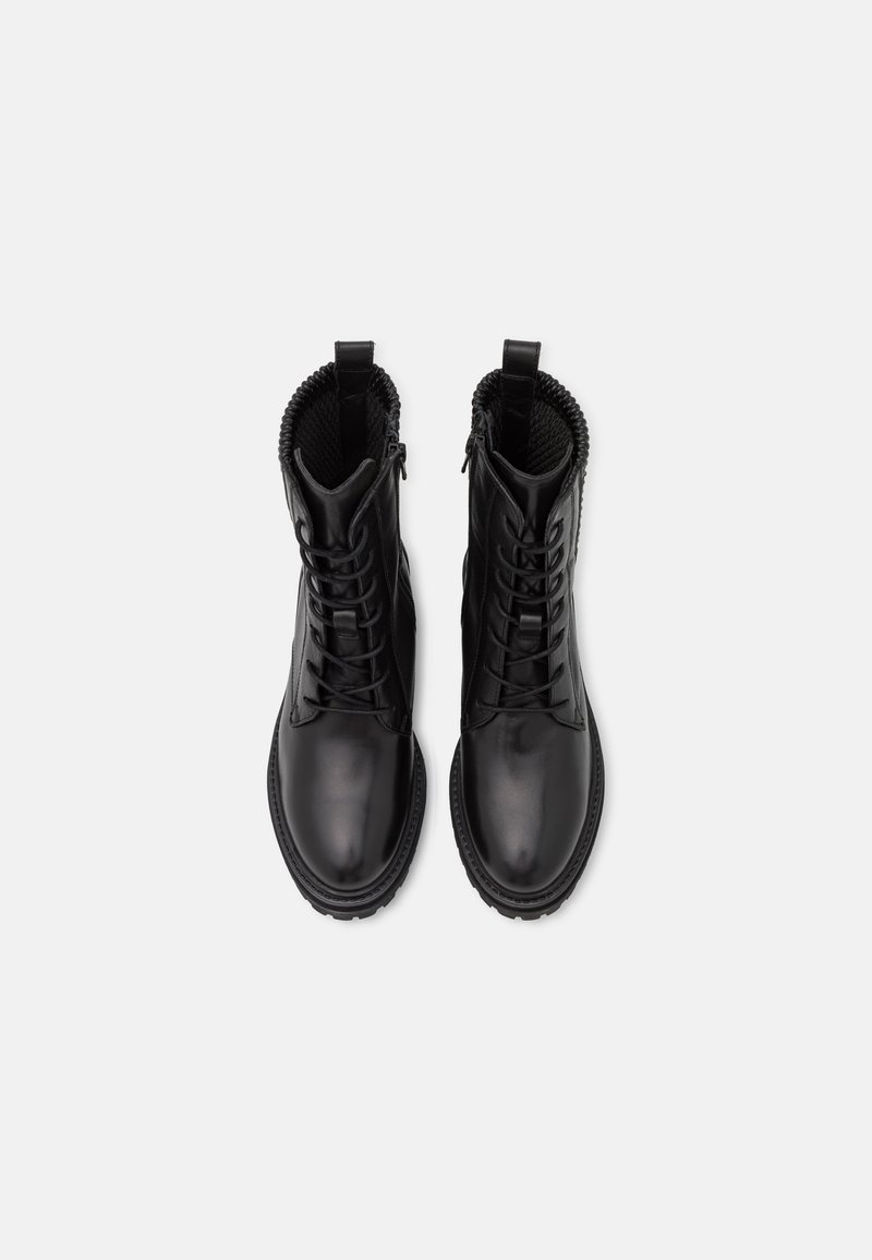 Ein Paar schwarze Leder Schnür-Stiefel im Combat-Stil mit massiven Sohlen, von oben auf einem weißen Hintergrund betrachtet.