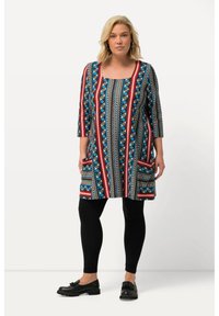 Túnica estampada con escote cuadrado, que presenta patrones geométricos en azul, rojo y crema, con mangas de tres cuartos y bolsillos laterales.