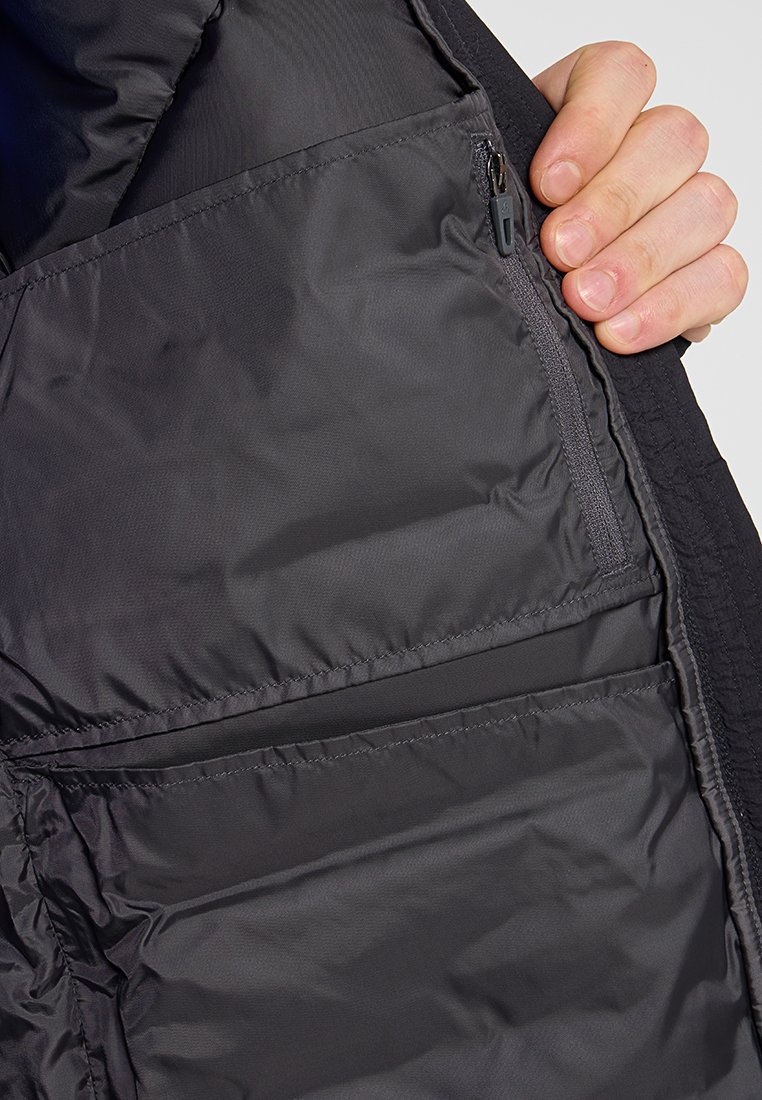 Schwarze Steppjacke innen mit gestepptem Futter, Reißverschlusstasche und glatter Textur. Verfügt über markante Nähte und mehrere Taschenstile.