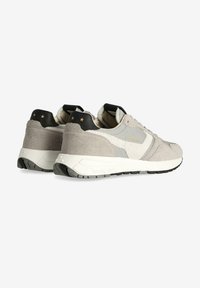 Sneaker in suede grigio e beige con tallone nero, suola bianca e dettagli dorati. Presentano materiali testurizzati e un design a pannelli contrastanti.