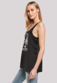 Schwarzes Tanktop mit breiten Trägern und einem grafischen Frontdesign sowie Text. Getragen mit hellblauen Jeans.