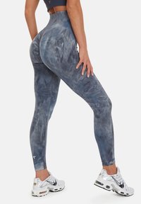Hög midja leggings i ett blågrått tie-dye mönster, tillverkade av stretchigt tyg. Har en logotypdetalj vid ankeln och en slät textur.