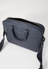 Mørkeblå læder laptop taske med en tekstureret overflade, dobbelt greb og en aftagelig skulderrem; har en lynlås lukning og diskret branding.