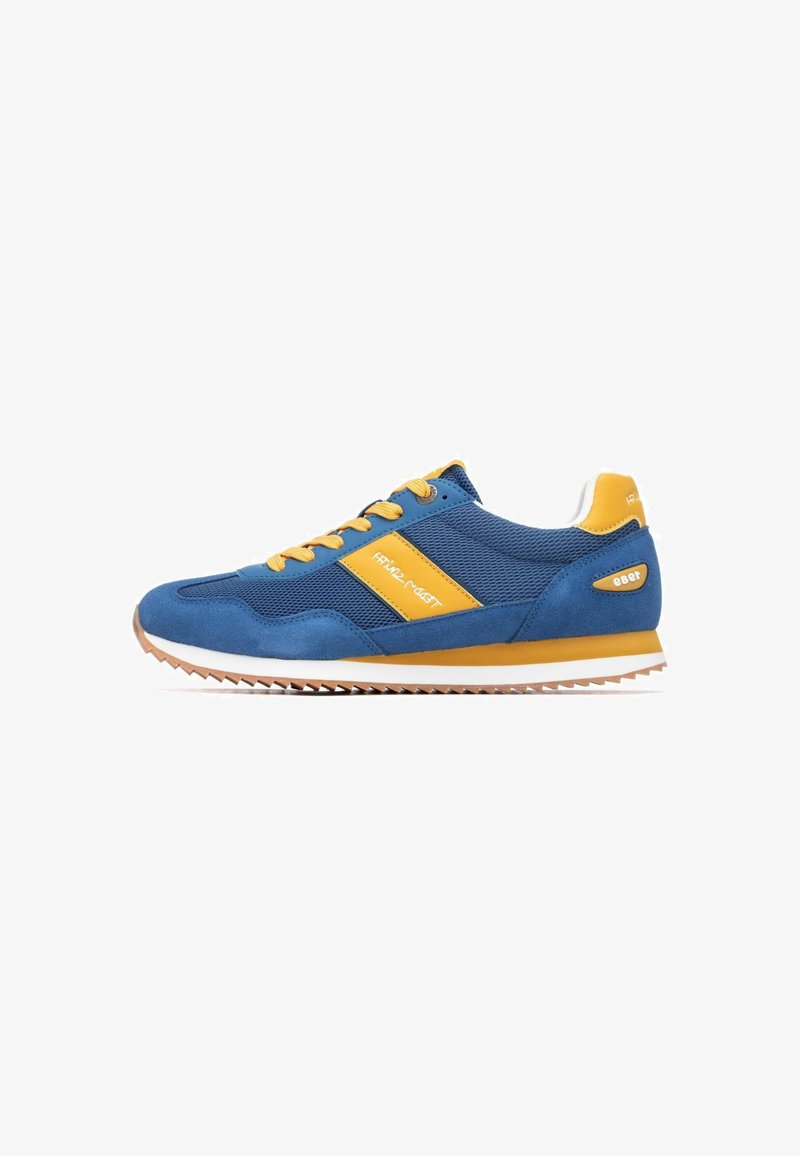 Chaussures de sport bleues avec des accents jaunes et des lacets, en mesh et en daim. Elles présentent une semelle texturée avec un motif en zigzag et un détail de logo.