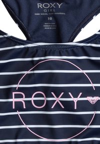 Navy blue uimavaatteet valkoisilla raidoilla, jossa on vaaleanpunainen "ROXY" -logo ja ympyräkuvio. Valmistettu sileästä kankaasta, sopii uintiin.
